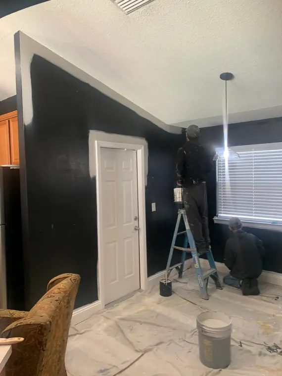 Francisco Painting crew cutting in a black accent wall with the furniture covered and floors protected