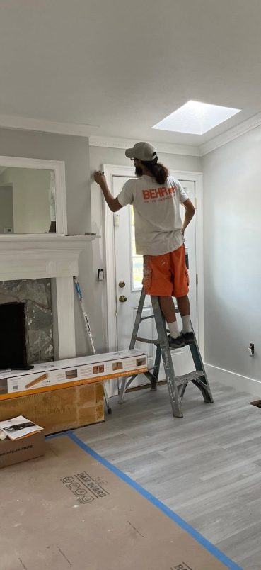 Painter finishing trim and door enamel work beside a fireplace